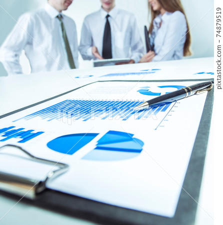 digital tablet and financial charts on the desktop in the background of the business team 74879519