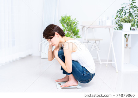 Middle-aged woman worried about riding a scale 74879860