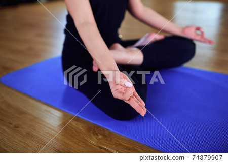 Girl sitting in a yoga pose gym. Relaxation, meditation, health 74879907
