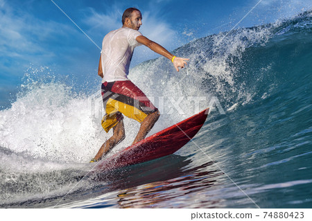 Male surfer on a blue wave 74880423