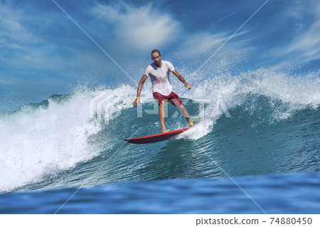 Male surfer on a blue wave Male surfer on a blue wave 74880450