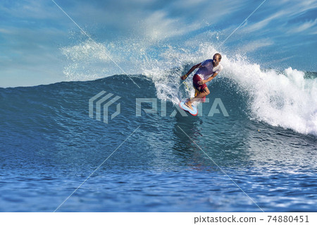 Male surfer on a blue wave Male surfer on a blue wave 74880451