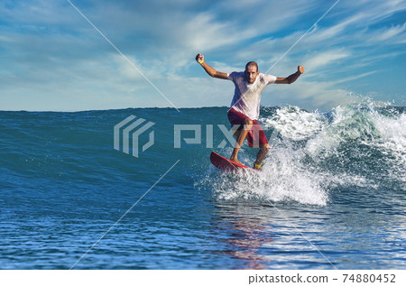 Male surfer on a blue wave Male surfer on a blue wave 74880452