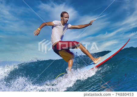 Male surfer on a blue wave 74880453