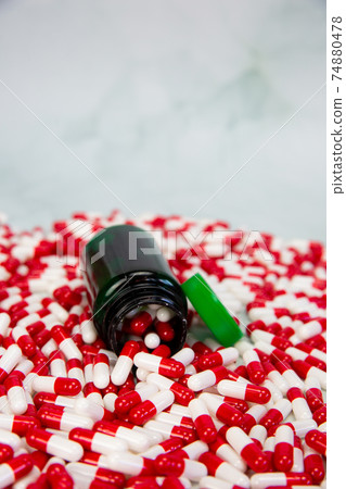 Bottle with red and white capsule on white background, Vitamin,drugs or pharmaceutical medication background, Health, medical and business concept 74880478