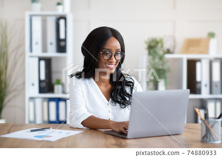 Beautuful black businesswoman working with laptop computer at desk in office Beautuful black businesswoman working with laptop computer at desk in office 74880933