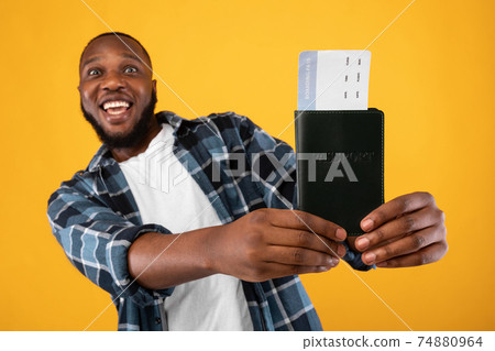 Excited Black Man Showing Travel Tickets Posing Over Yellow Background 74880964