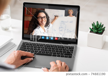 Unrecognizable woman sitting at desk using laptop, having video call Unrecognizable woman sitting at desk using laptop, having video call 74881190