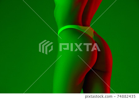 Beautiful female back on green background in neon light. Beauty, cosmetics, spa, depilation, diet and treatment, fitness concept. 74882435