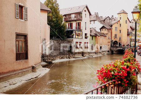 Annecy city water channel with red flowers and old buildings Annecy city water channel with red flowers and old buildings 74882736