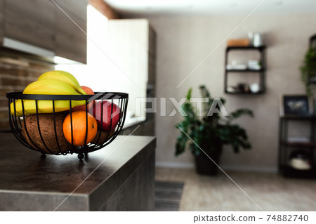 Fruits in fruit bowl on bar counter in stylish loft kitchen. Blurred background Fruits in fruit bowl on bar counter in stylish loft kitchen. Blurred background 74882740