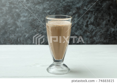 Glass of chocolate milkshake on white wooden table 74883815