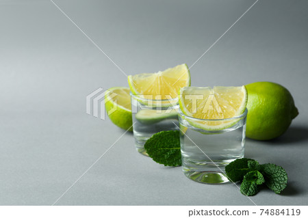 Shots, lime slices and mint on gray background Shots, lime slices and mint on gray background 74884119