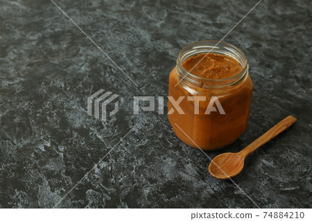 Jar with zucchini caviar and wooden spoon on black smokey background Jar with zucchini caviar and wooden spoon on black smokey background 74884210