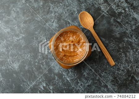 Jar with zucchini caviar and wooden spoon on black smokey background Jar with zucchini caviar and wooden spoon on black smokey background 74884212