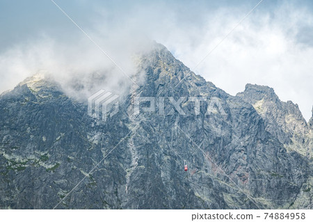 View of the Lomnicky stit peak, famous rocky summit in High Tatras, Slovakia. Cloudy windy day. View of the Lomnicky stit peak, famous rocky summit in High Tatras, Slovakia. Cloudy windy day. 74884958