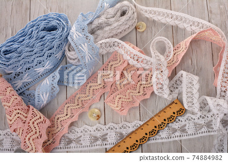 Pile of vintage cotton tapes and round buttons on wood background 74884982
