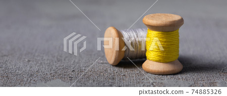 Illuminating Yellow and Ultimate grey colored threads wooden bobbins, banner 74885326