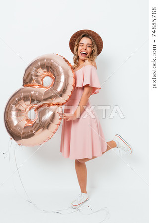 Joyful young woman wearing pink dress and straw hat posing 74885788