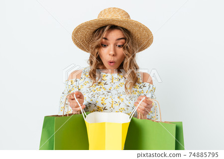 Curious beautiful young woman wearing summer dress and straw hat 74885795
