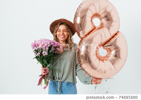 Joyful young woman laughing with eyes closed holding balloon Joyful young woman laughing with eyes closed holding balloon 74885800