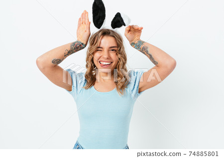 Cute young woman wearing toy easter bunny ears smiles 74885801
