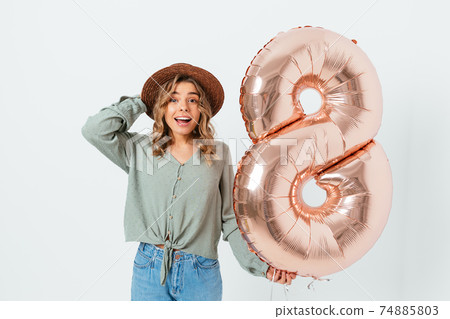 Portrait happy beautiful young woman holding eight-shaped balloon Portrait happy beautiful young woman holding eight-shaped balloon 74885803