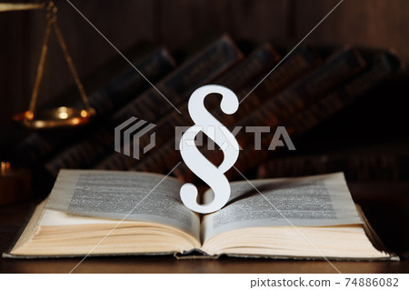 Paragraph sign and book in a courtroom Paragraph sign and book in a courtroom 74886082