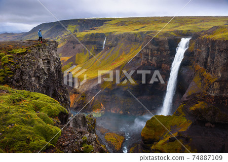 Hiker standing at the edge of the Haifoss waterfall in Iceland 74887109