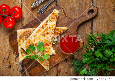 Close-up baked national oriental pastry with cheese filling, tomato sauce, greens, traditional Close-up baked national oriental pastry with cheese filling, tomato sauce, greens, traditional 74887868