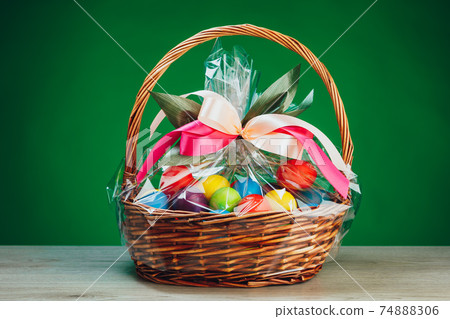 Easter gift basket with multicolor eggs, green background Easter gift basket with multicolor eggs, green background 74888306