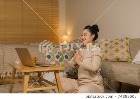 A woman who plays yoga while watching a computer A woman who plays yoga while watching a computer 74888605