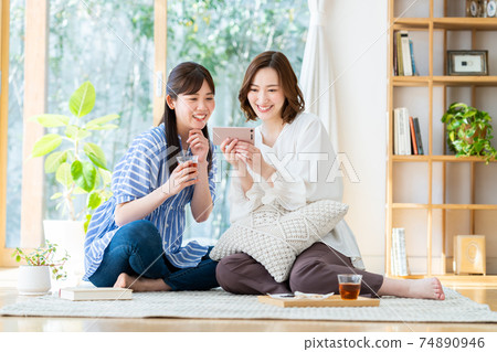 一個年輕的女人，看著她的智能手機上的視頻 74890946