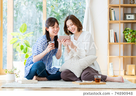 一個年輕的女人,看著她的智能手機上的視頻 一個年輕的女人,看著她的智能手機上的視頻 74890948