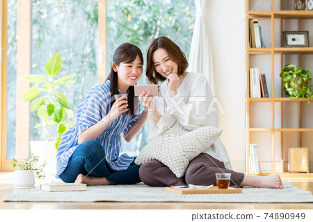 一個年輕的女人,看著她的智能手機上的視頻 一個年輕的女人,看著她的智能手機上的視頻 74890949