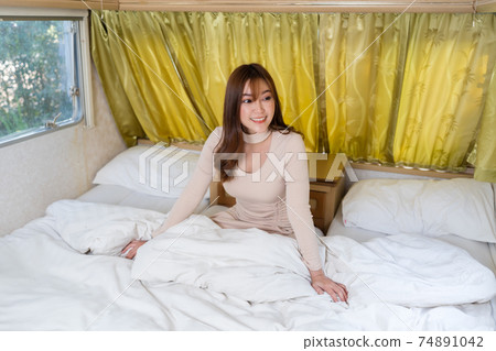 happy woman in bed of a camper RV van motorhome 74891042