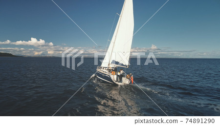 Closeup of yacht cruise at open sea with passengers aerial view. Sail boat at ocean with travelers Closeup of yacht cruise at open sea with passengers aerial view. Sail boat at ocean with travelers 74891290