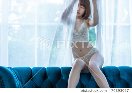 Asian woman taking off or putting bra on white Stock Photo