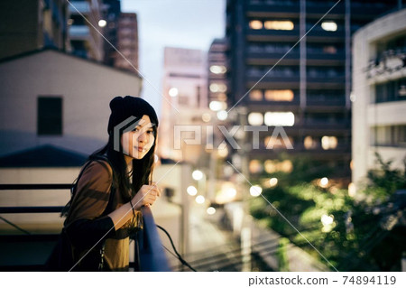 在屋頂上,一個有夜景和針織帽子的女人 在屋頂上,一個有夜景和針織帽子的女人 74894119