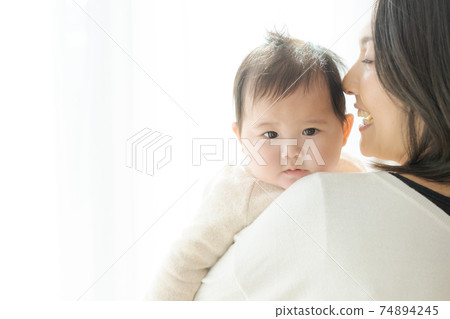A cute baby in its mother's arms 74894245