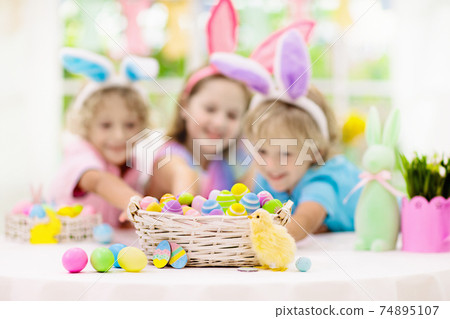 Kids on Easter egg hunt. Children dye eggs. 74895107