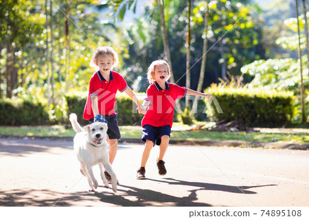 Child walking dog. Kids and puppy. Boy and pet. 74895108