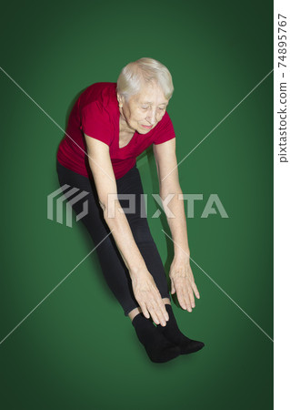 Senior woman wearing sportswear while gymnastic exercising in the living room 74895767