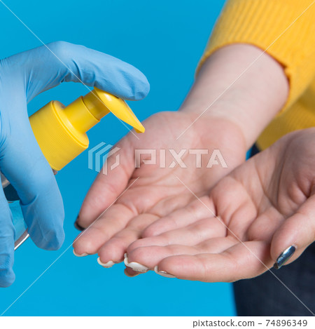 medical concept, girl washes her hands with disinfectant liquid, on a blue background, close-up medical concept, girl washes her hands with disinfectant liquid, on a blue background, close-up 74896349