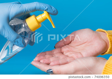 hands disinfect with a disinfectant, the concept of protection against viruses and pathogenic bacteria, on a blue background hands disinfect with a disinfectant, the concept of protection against viruses and pathogenic bacteria, on a blue background 74896350