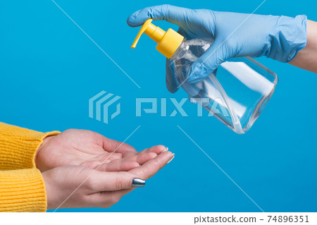 the concept of protection against coronovirus and pathogenic bacteria, hands are treated with a disinfectant, on a blue background the concept of protection against coronovirus and pathogenic bacteria, hands are treated with a disinfectant, on a blue background 74896351