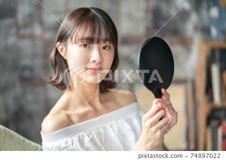 Late teenage girls looking in a hand mirror 74897022