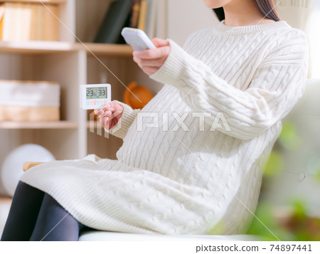 看著溫濕度計並通過遙控器操作的孕婦4：3 74897441