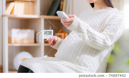 看著溫濕度計並通過遙控器操作的孕婦16:9 看著溫濕度計並通過遙控器操作的孕婦16:9 74897442