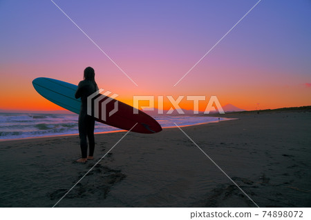 Surfers and Mt. Fuji standing on the beach at dusk Surfers and Mt. Fuji standing on the beach at dusk 74898072
